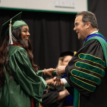 commencement President Zenger President Zenger shakes hands with a graduate and passes a diploma