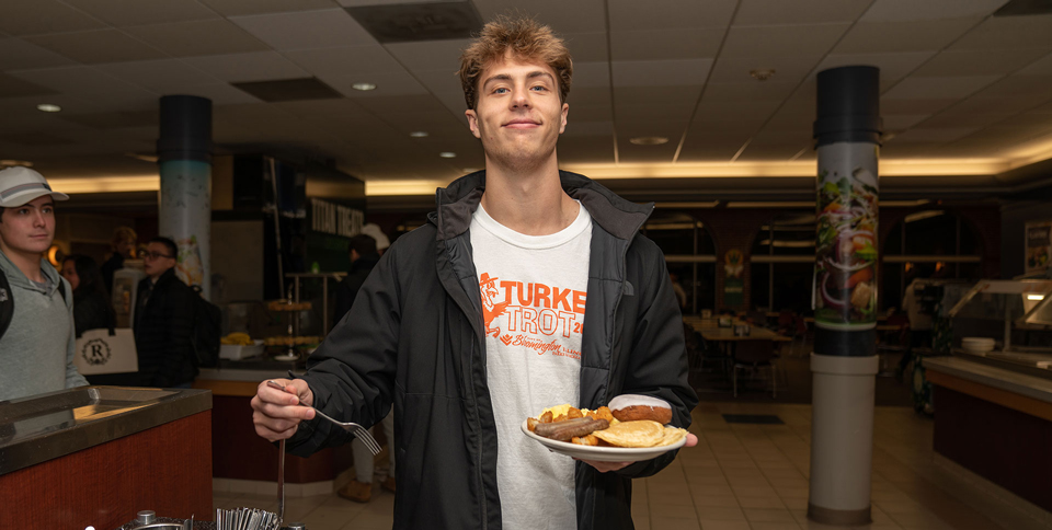 Student with a plate filled with breakfast foods during Late Night Breakfast