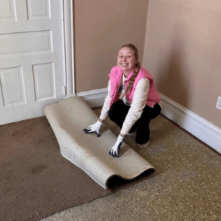 Abbie Graue rolling up carpet during renovations