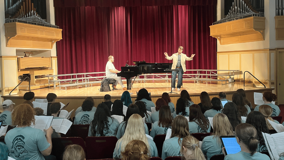 Director of Choral Activities Cody S Parrott conducts from stage of Westbrook Auditorium in Pressr Hall