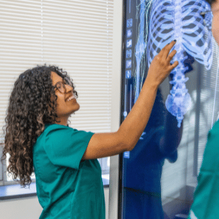 Nursing student tapping monitor with full size skeleton