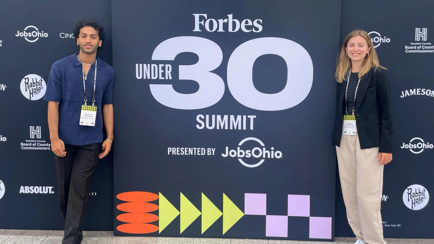 Roshan and Joelle pose in front of Forbes banner