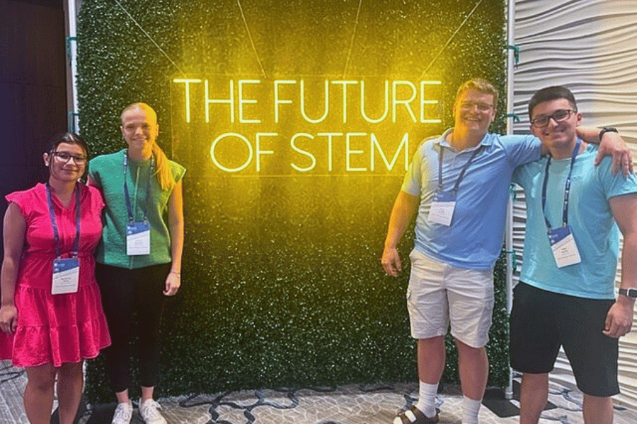 IWU Noyce Scholars standing in front of neon sign that says "the future of stem"